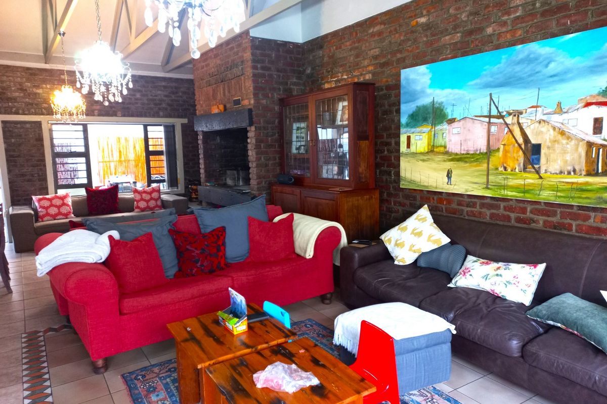 Spacious living room featuring exposed brick walls, a vaulted ceiling with timber beams, and a large built-in fireplace.