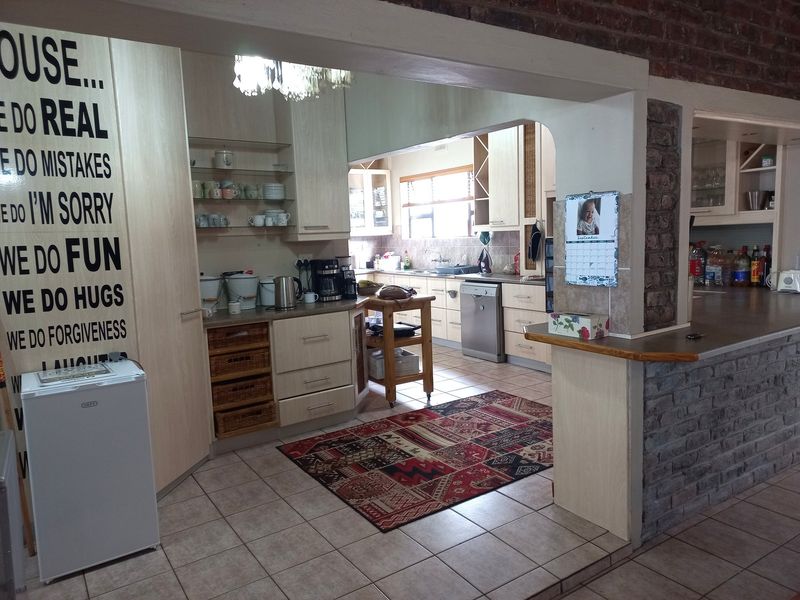 A functional kitchen featuring light wood cabinetry, tiled flooring, and an exposed brick breakfast bar, offering ample storage and workspace.