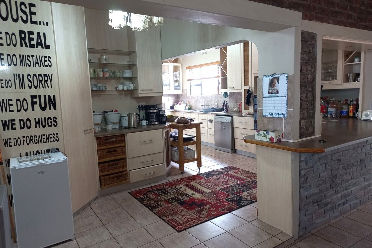 A functional kitchen featuring light wood cabinetry, tiled flooring, and an exposed brick breakfast bar, offering ample storage and workspace.