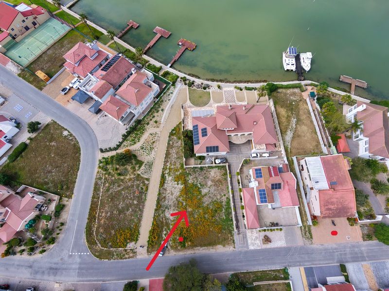 Aerial view of a vacant residential plot situated in a developed estate, featuring street access and proximity to the waterfront.