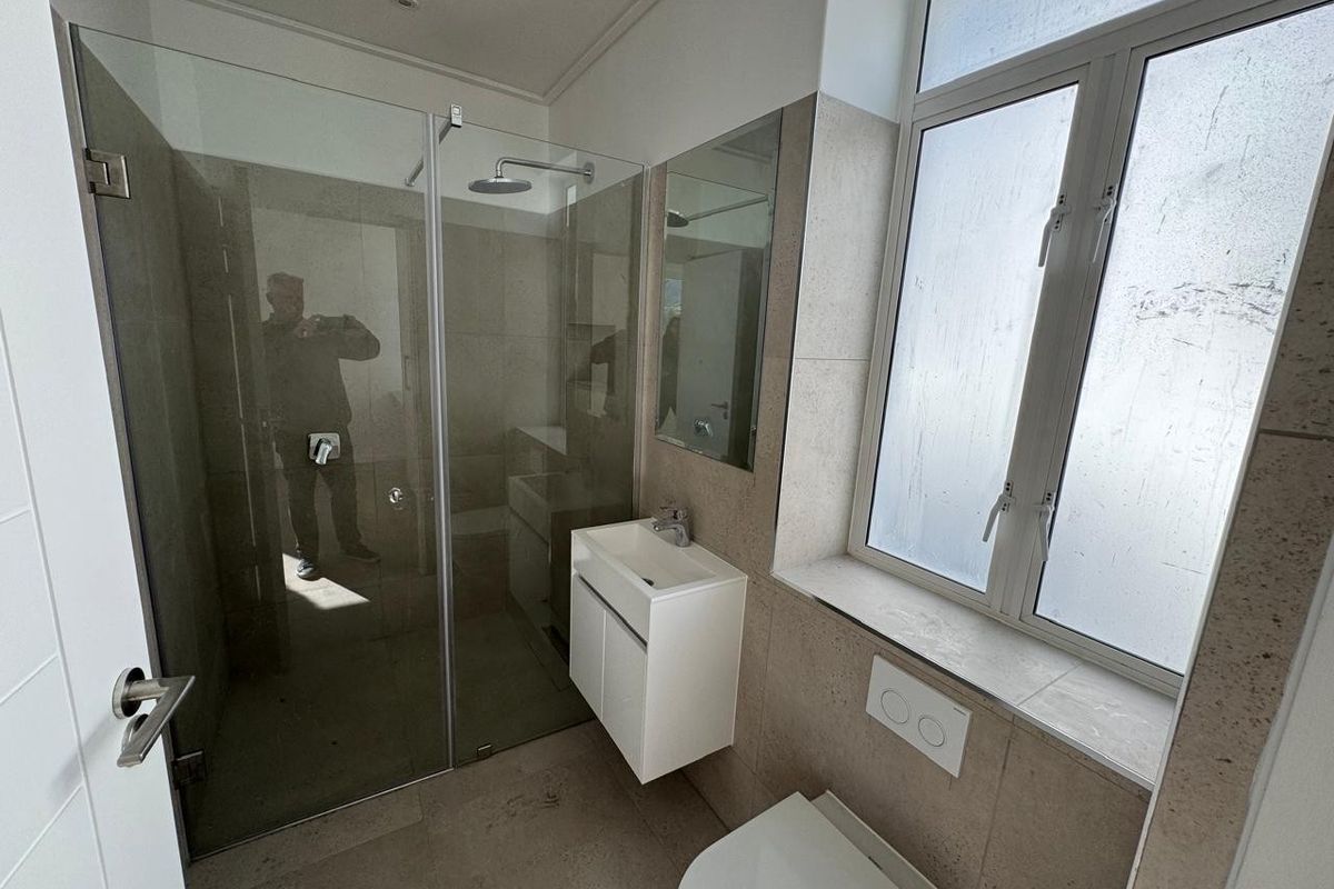 Modern bathroom featuring a glass shower enclosure, wall-mounted vanity with basin, and a wall-hung toilet with a concealed cistern.