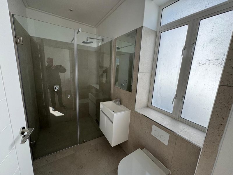 Modern bathroom featuring a glass shower enclosure, wall-mounted vanity with basin, and a wall-hung toilet with a concealed cistern.