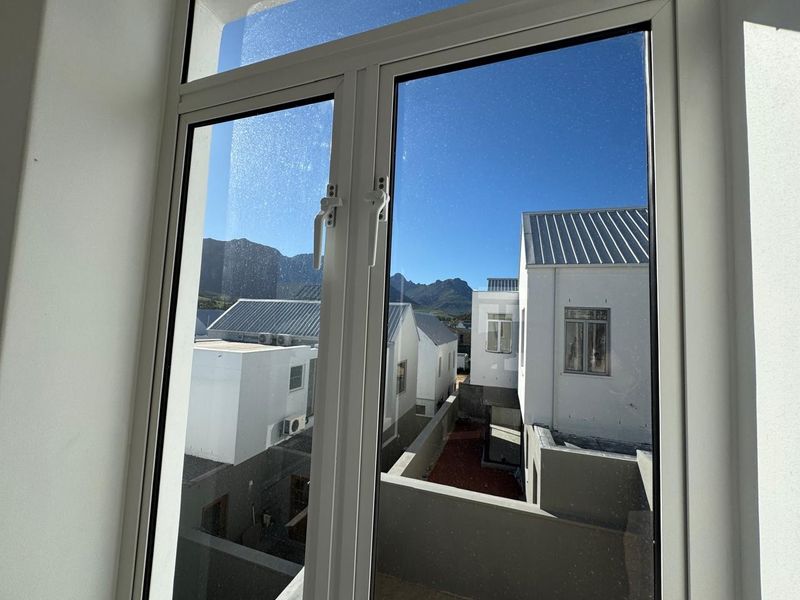 A view from an interior window looking out over a modern residential estate with mountain vistas in the background.