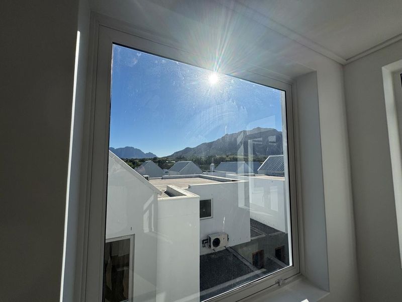 A clear view of the surrounding estate and mountain range captured through a large, modern window.