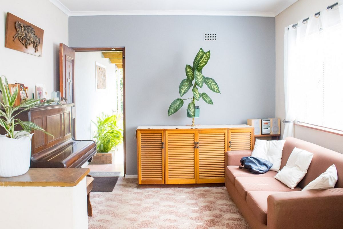 A living room featuring neutral wall tones, a window for natural light, and carpet flooring, providing a comfortable and functional living space.