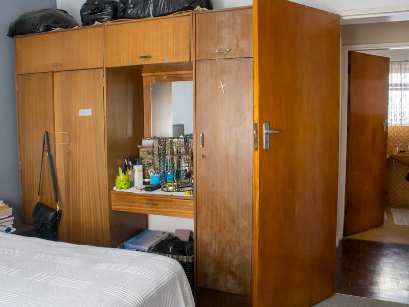 Bedroom featuring a large built-in wooden wardrobe with an integrated vanity mirror and parquet flooring.