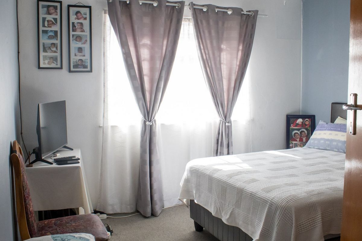 A functional bedroom featuring carpeted flooring and a window, providing a comfortable and well-lit space.