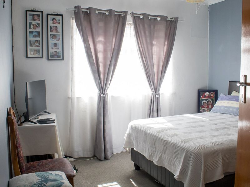 A functional bedroom featuring carpeted flooring and a window, providing a comfortable and well-lit space.