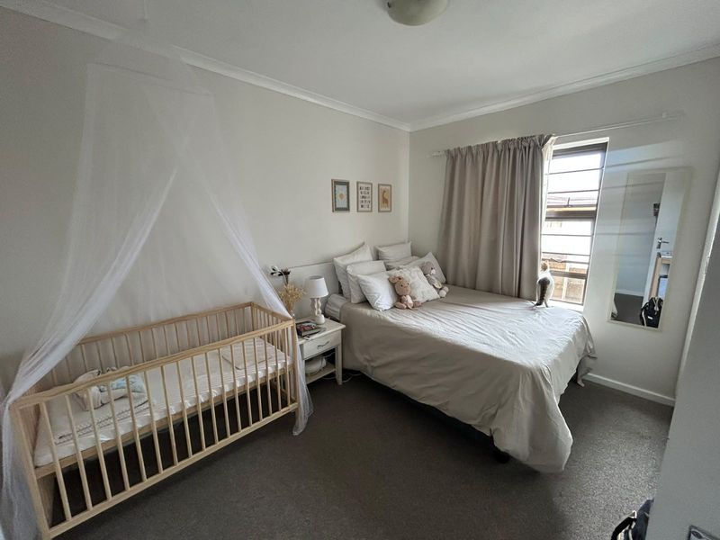 A functional bedroom featuring carpeted flooring, neutral wall finishes, and a window fitted with security bars.