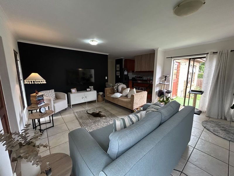 Open-plan living area featuring tiled flooring, a dark accent wall, and direct access to the rear garden through a sliding glass door.