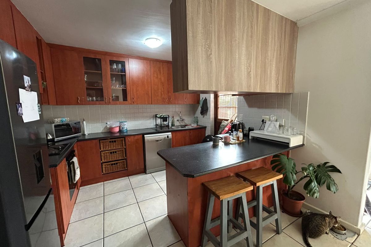 A functional kitchen featuring wood-tone cabinetry, dark countertops, a breakfast bar, and tiled flooring, offering a practical layout for daily meal preparation.