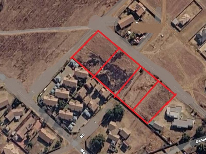 An aerial view showing multiple vacant residential plots of land with street access in a developing suburban area.