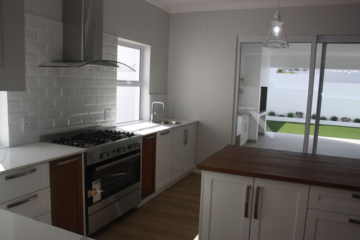 Modern kitchen featuring a gas stove, subway tile backsplash, and a central island, with seamless access to the outdoor patio area.