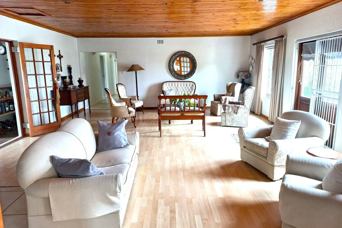 Spacious living room featuring a warm timber-clad ceiling, light laminate flooring, and natural light through sliding glass doors and a classic french door.