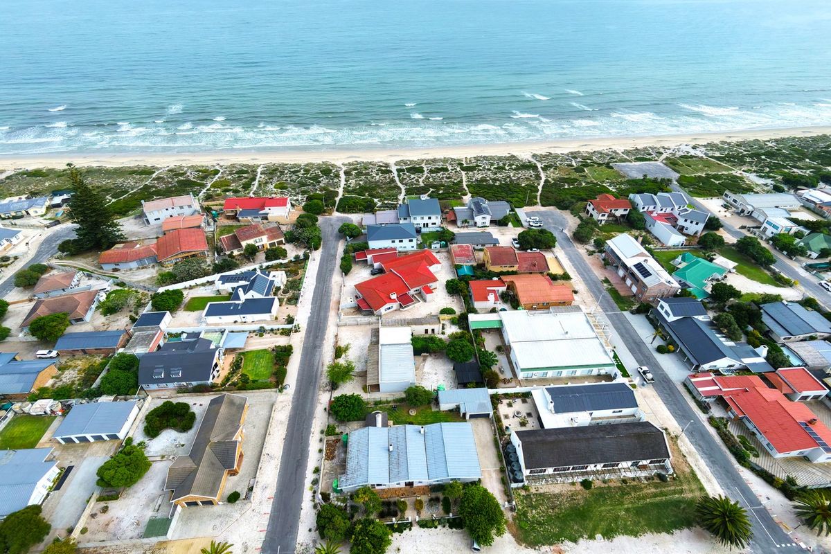 An aerial view of a coastal residential neighborhood showing the proximity of the properties to the beach and ocean.