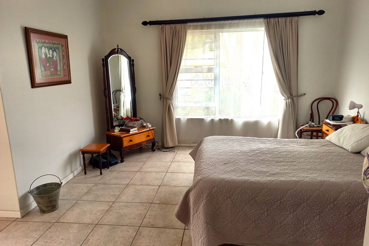 A spacious bedroom featuring neutral tiled flooring and a large window that allows for natural light.