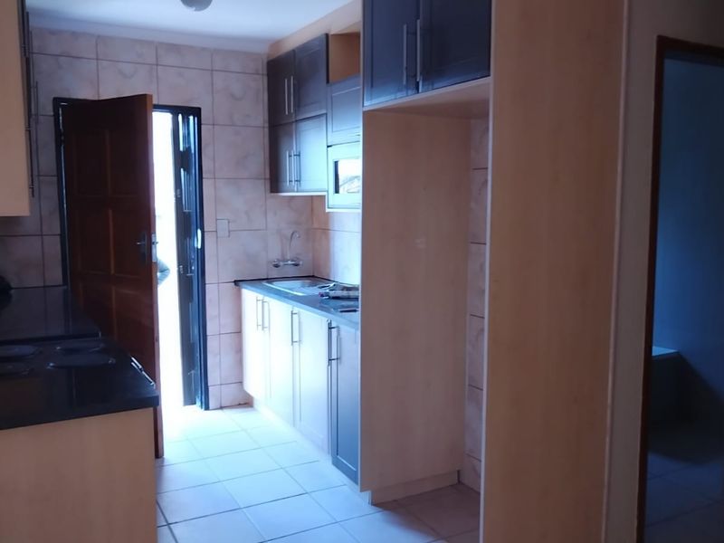 A functional kitchen featuring built-in cabinetry, laminate countertops, and tiled finishes, offering a clean and practical layout for daily use.