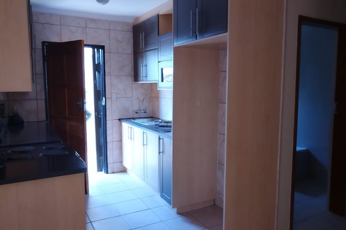 A functional kitchen featuring built-in cabinetry, laminate countertops, and tiled finishes, offering a clean and practical layout for daily use.