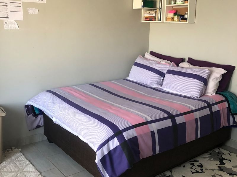 A functional bedroom featuring tiled flooring and a wall-mounted shelving unit, providing a neutral base for personalization.