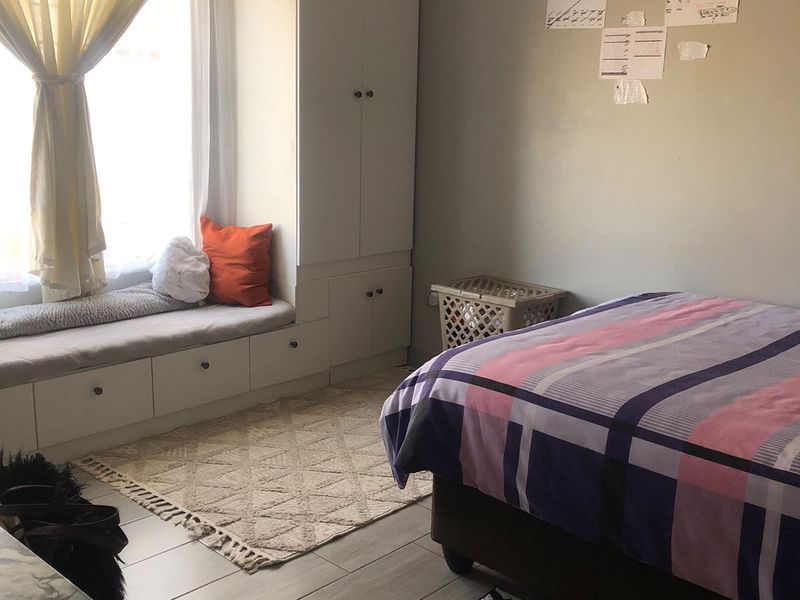 A bedroom featuring tiled flooring, built-in cupboards, and a custom window seat with integrated storage.