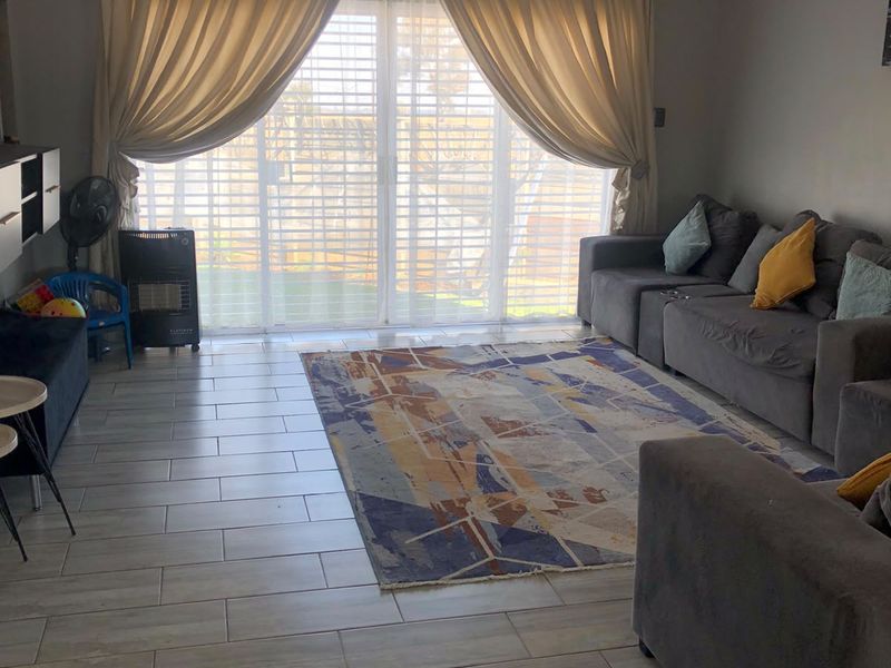 A bright living room featuring tiled flooring and a large sliding glass door that provides access to the outdoor area.