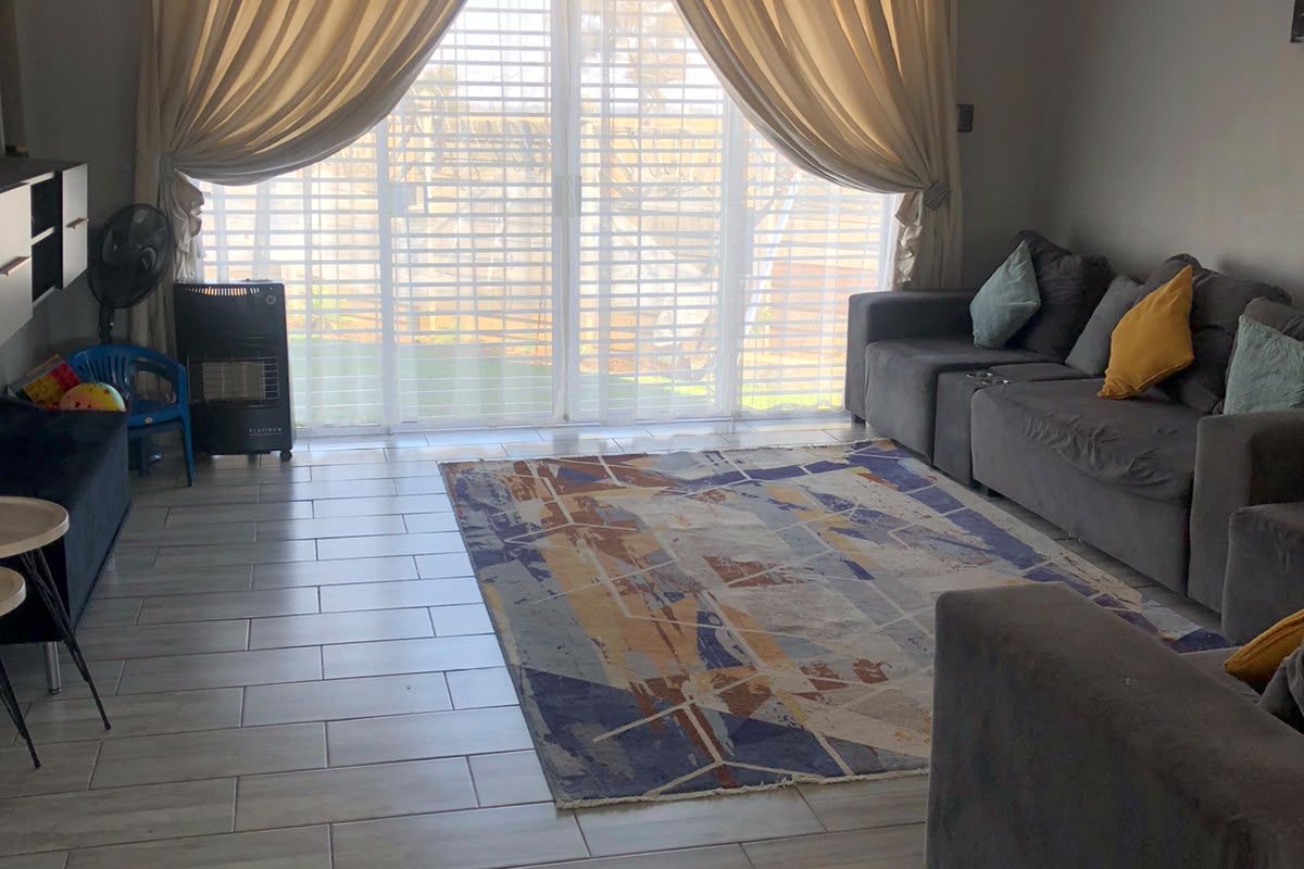 A bright living room featuring tiled flooring and a large sliding glass door that provides access to the outdoor area.