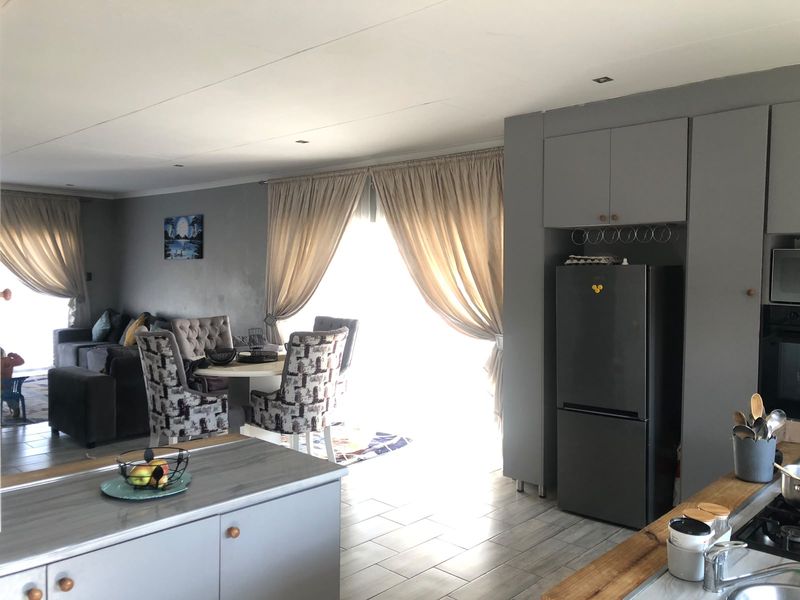 Open-plan living and kitchen area featuring modern grey cabinetry, a kitchen island with a gas hob, and tiled flooring throughout.