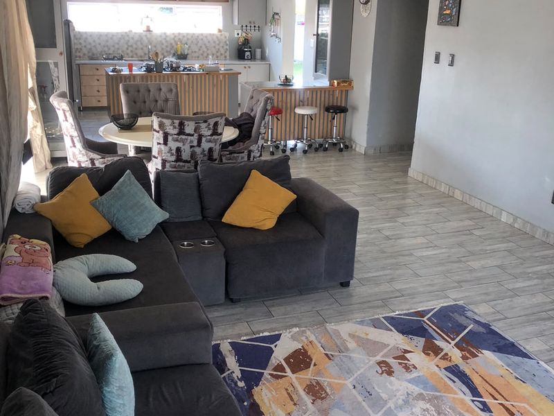 Spacious open-plan living area featuring a modern kitchen with island, breakfast bar, and neutral tiled flooring throughout.