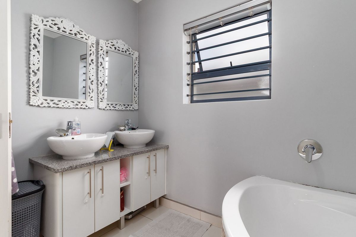 A well-maintained bathroom featuring a double vanity with vessel sinks, granite countertops, built-in cabinetry, and a modern bathtub.