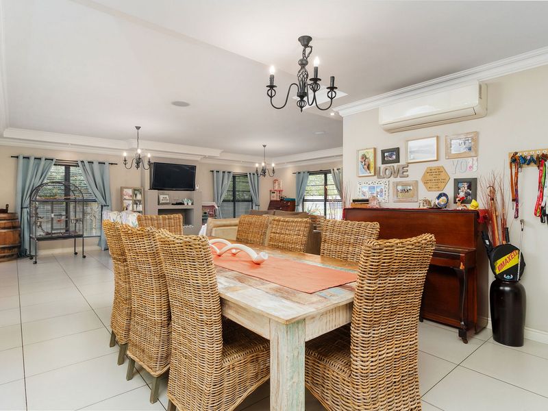 Spacious open-plan living and dining area featuring neutral tiled flooring, decorative cove cornicing, and split-system air conditioning for year-round comfort.