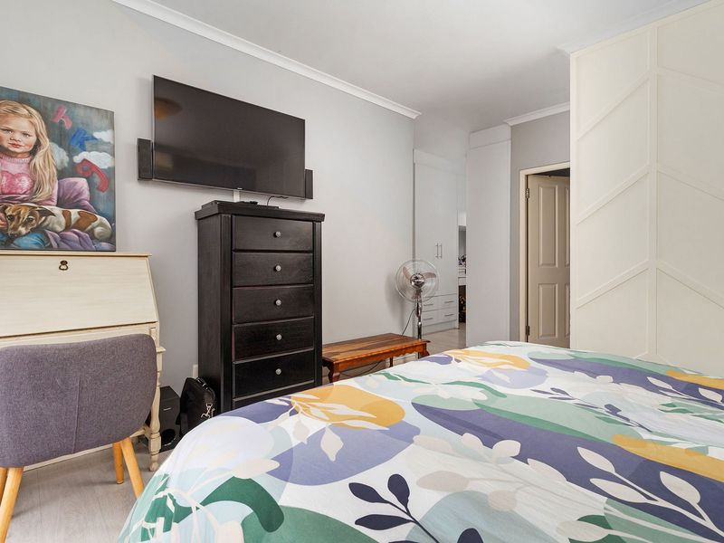 A well-maintained bedroom featuring built-in cupboards, neutral wall finishes, and decorative coving, providing a clean and functional living space.