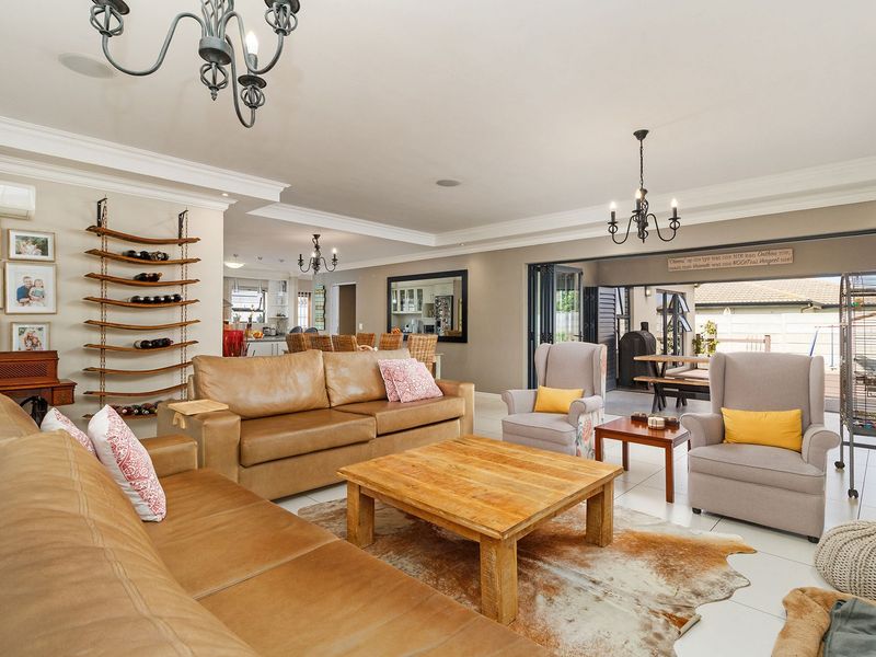 Spacious open-plan living area featuring tiled floors, crown molding, recessed lighting, and bi-fold doors leading to an outdoor patio space.