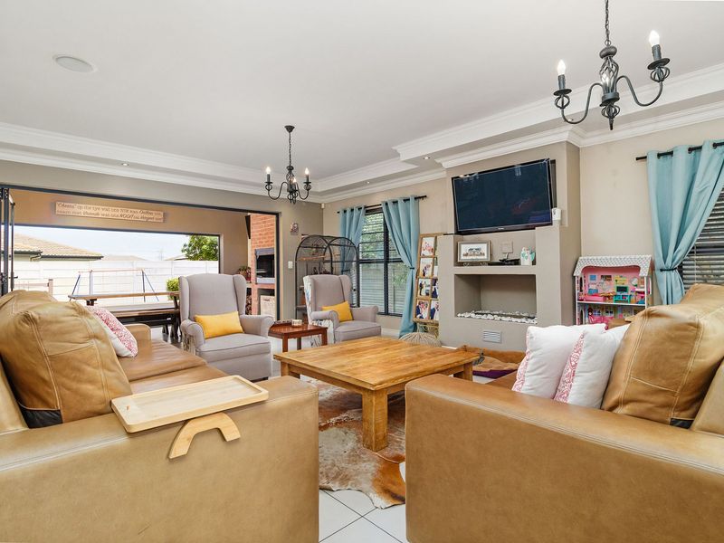 Spacious living room featuring a built-in fireplace, crown molding, and large sliding doors that open to an outdoor patio area.