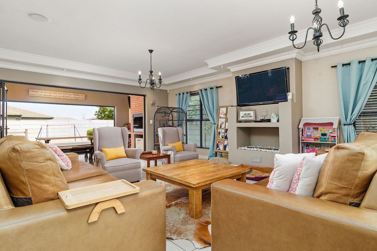 Spacious living room featuring a built-in fireplace, crown molding, and large sliding doors that open to an outdoor patio area.