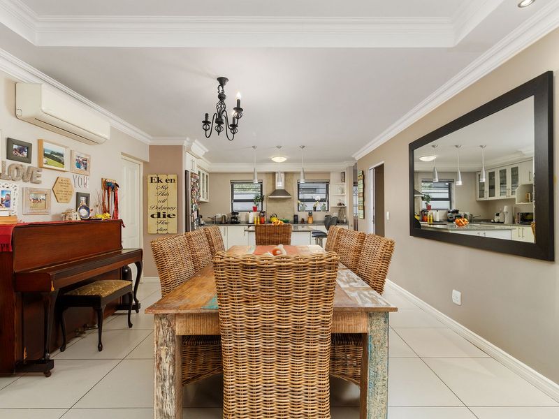 Spacious open-plan dining and kitchen area featuring tiled floors, crown molding, recessed lighting, and a functional kitchen layout with built-in cabinetry.