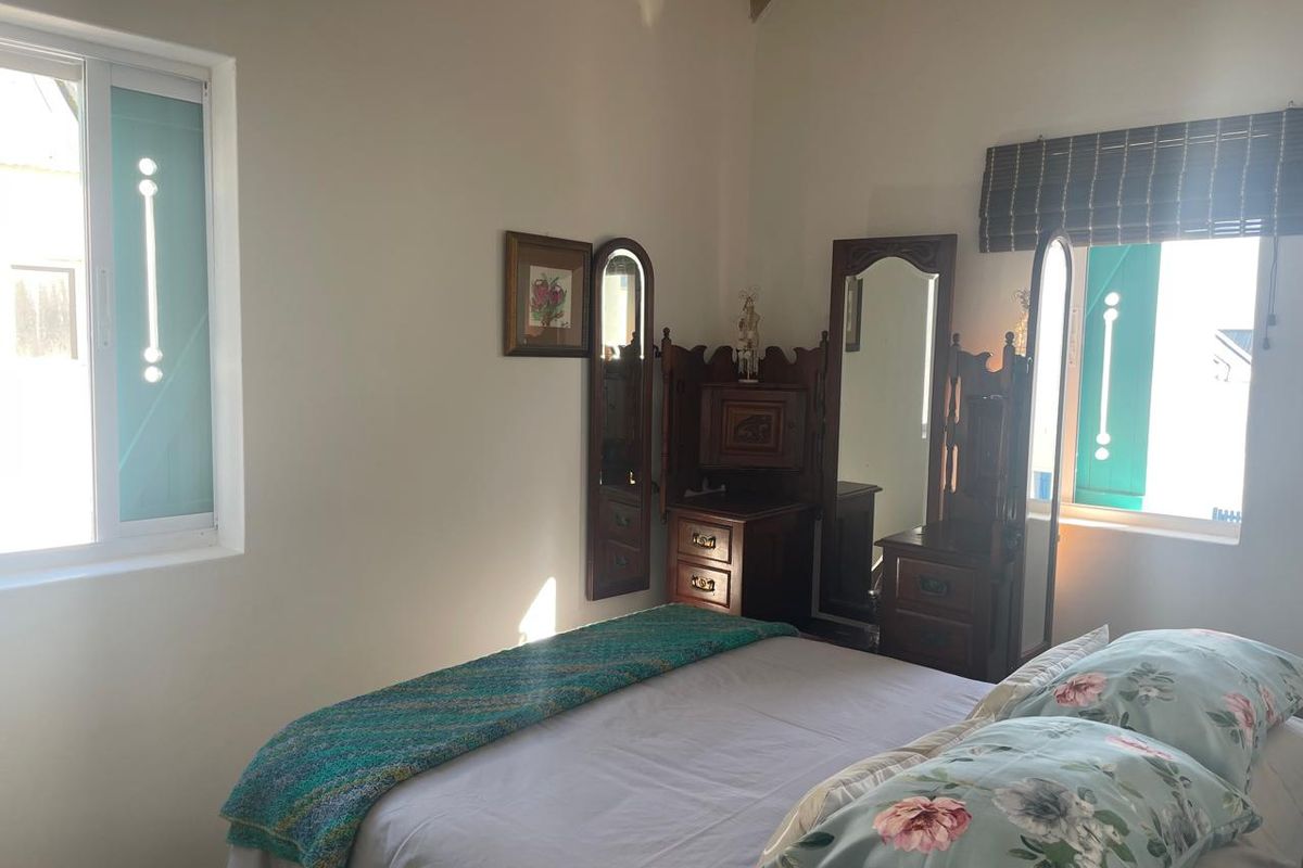 A bedroom featuring a vaulted ceiling and dual sliding windows, providing natural light and a simple, functional layout.