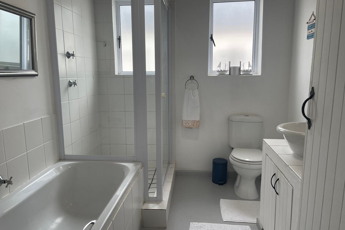 A functional bathroom featuring a built-in bathtub, separate glass shower enclosure, toilet, and a vanity cabinet with a vessel sink.