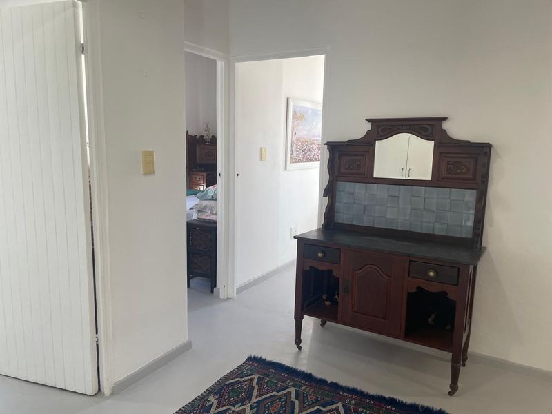 A neutral hallway connecting multiple rooms, featuring painted flooring and simple architectural finishes.