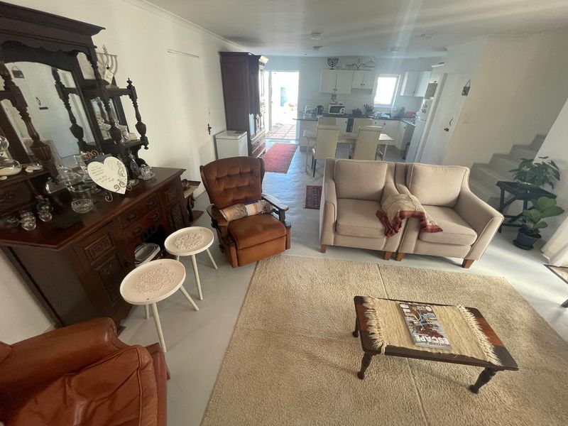 Open plan living and kitchen area featuring neutral flooring, white cabinetry, and direct access to an outdoor space.