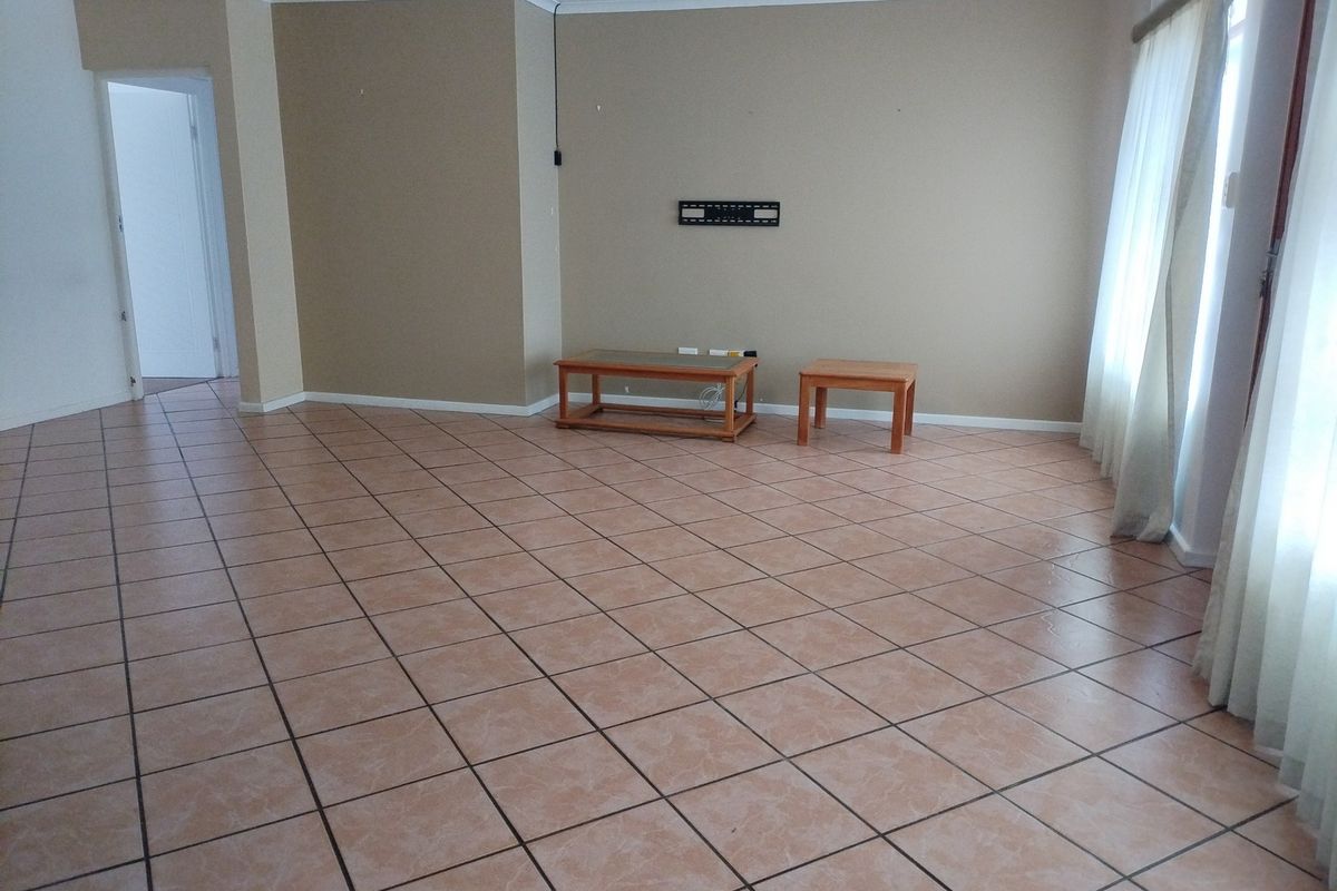 Spacious living area featuring neutral wall tones, tiled flooring, and a wall-mounted television bracket, offering a clean and versatile space for customization.