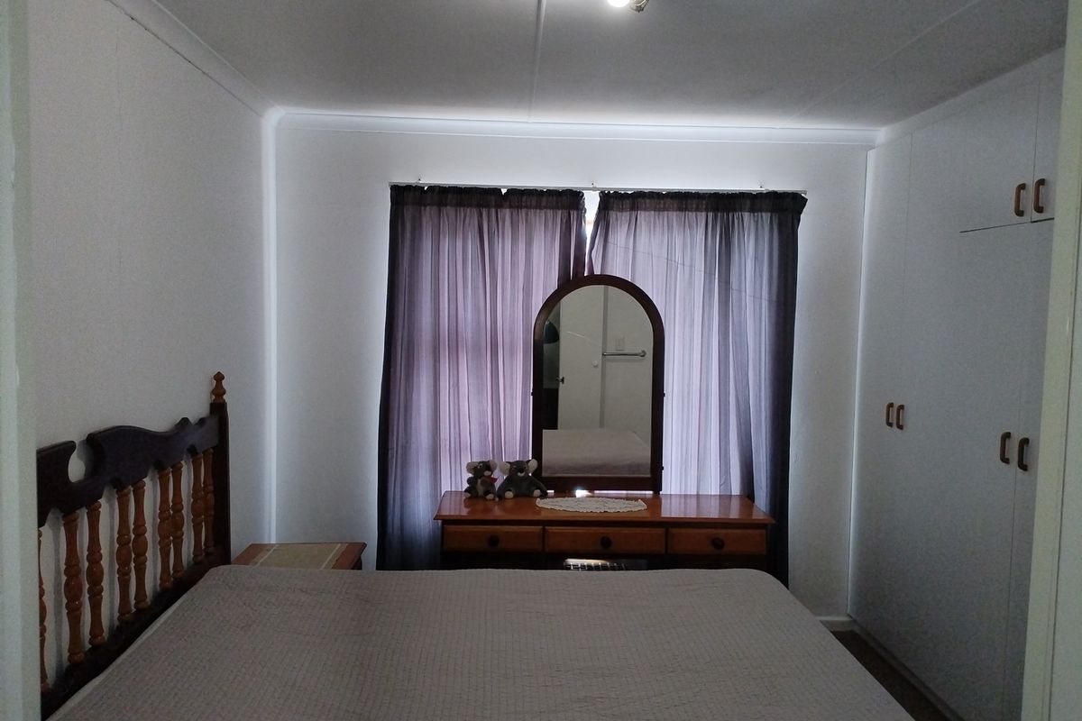 A functional bedroom featuring built-in cupboards and neutral wall finishes, providing a clean and practical space.