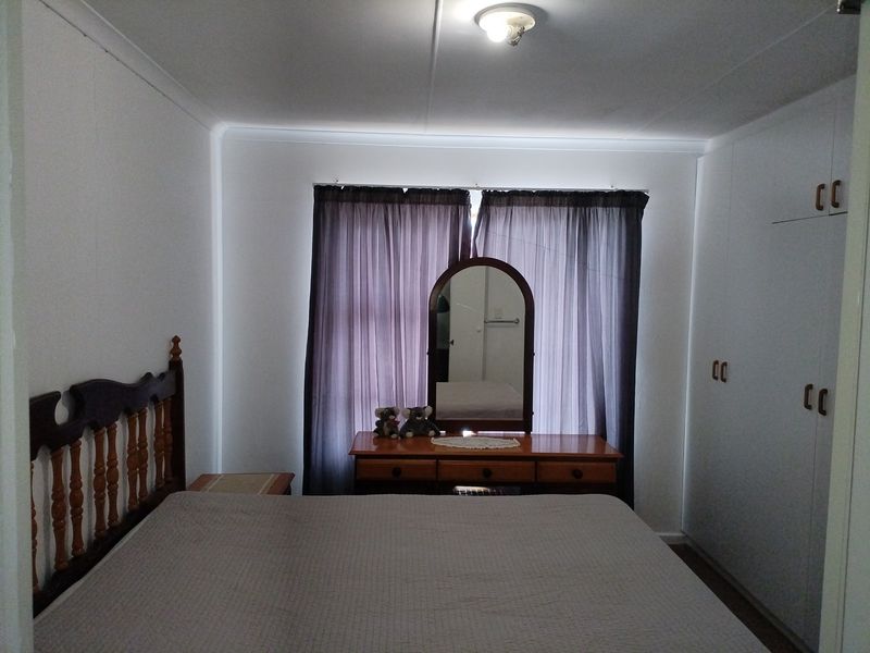 A functional bedroom featuring built-in cupboards and neutral wall finishes, providing a clean and practical space.