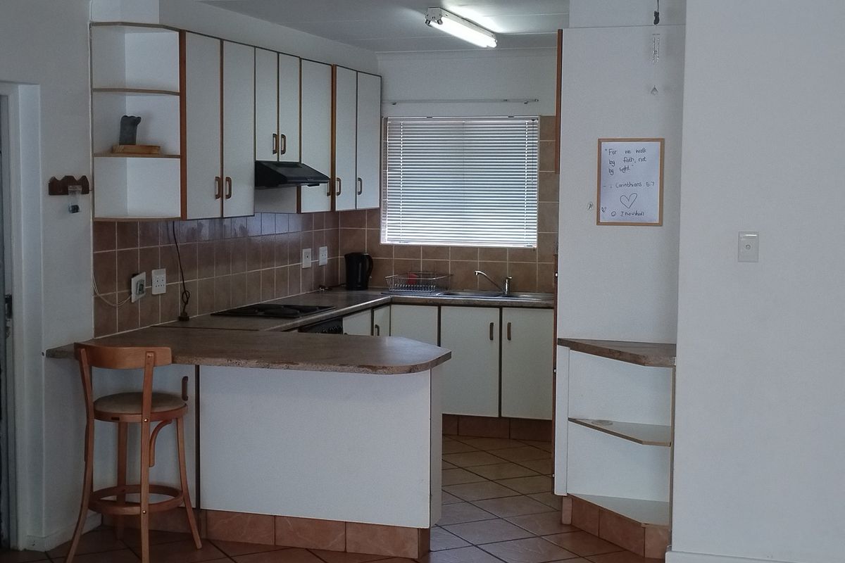A functional kitchen featuring white cabinetry, tiled backsplash, laminate countertops, and a breakfast bar, providing a practical layout for daily meal preparation.