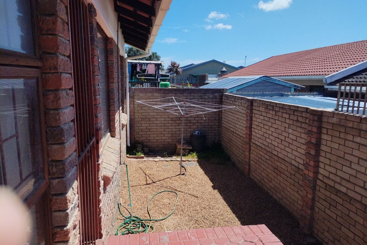 A private rear courtyard featuring a paved patio area, gravel ground cover, and secure brick boundary walls, offering a functional outdoor space.
