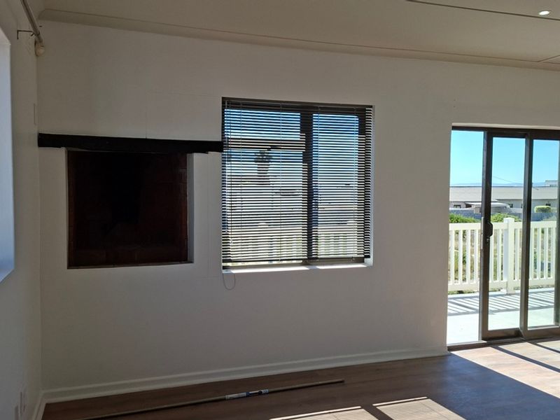 An empty living room featuring a built-in fireplace, laminate flooring, and sliding glass doors leading to an outdoor balcony area.