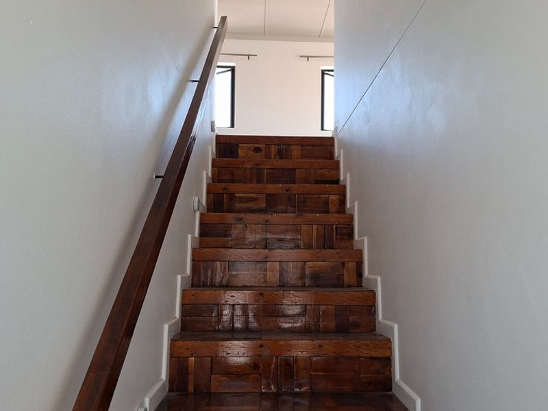 A staircase featuring wooden treads and a matching handrail, leading to an upper level landing.