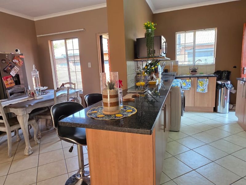 Open-plan kitchen and dining area featuring granite countertops, built-in cabinetry, and ceramic floor tiles, providing a functional space for cooking and dining.