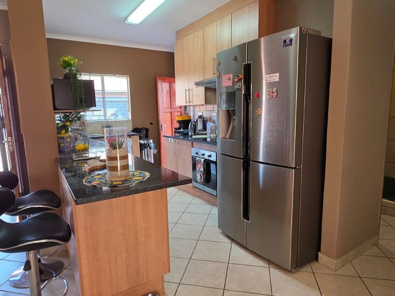 Open-plan kitchen featuring a breakfast bar island, granite countertops, and built-in cabinetry, seamlessly connecting to the living area and outdoor access.
