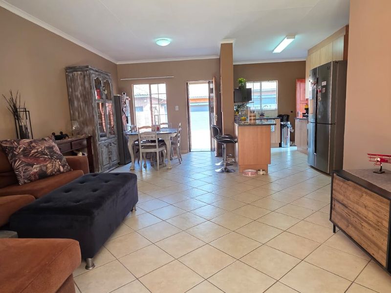 Open-plan living and kitchen area featuring tiled flooring, neutral wall tones, and a functional kitchen island layout.