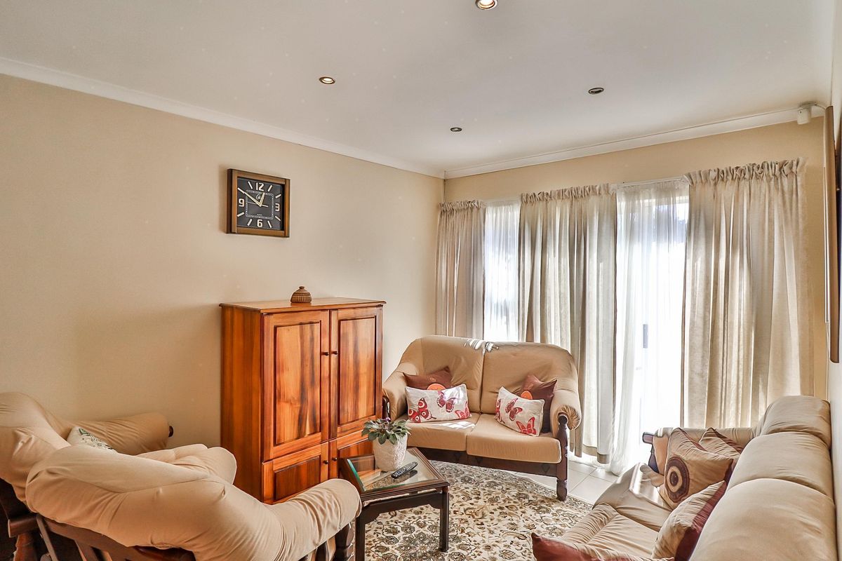 A comfortable living room featuring tiled flooring, recessed downlighting, and a sliding glass door providing natural light.